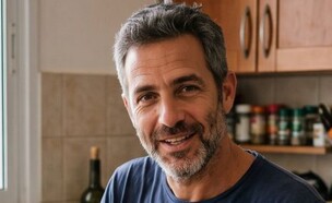 גבר יושב במטבח, מסתכל למצלמה (AI: mako)