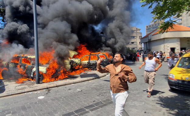 אנשים בורחים לצד מכוניות שרופות לאחר תקיפה בצידון אנשים בורחים לצד מכוניות שרופות לאחר תקיפה בצידון